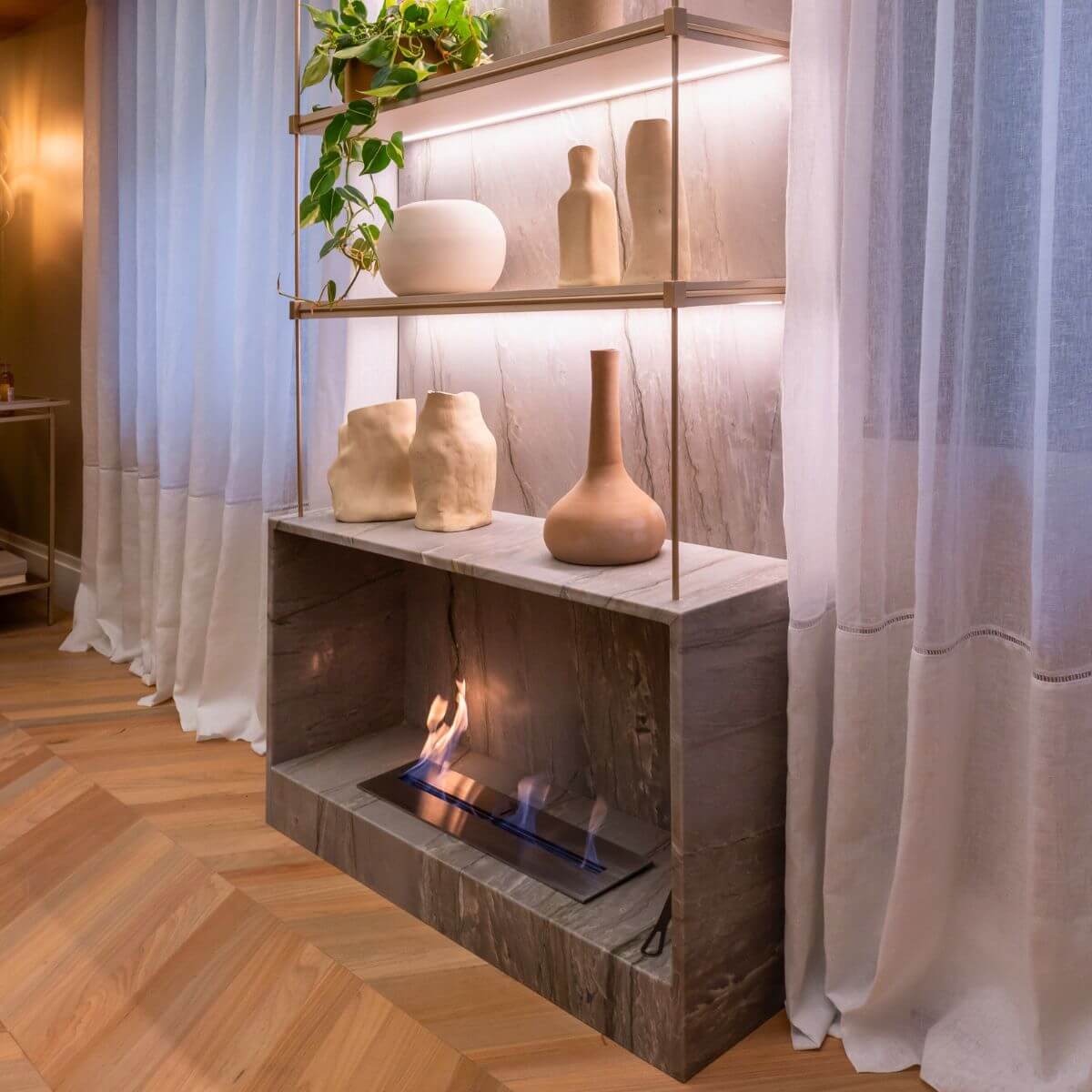 Sala de estar com lareira ecológica Somer instalada em nicho de pedra.